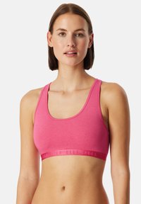 Roze sportbeha van zacht materiaal, met een scoop halslijn, brede bandjes en een vaste band met merklogo aan de onderkant.