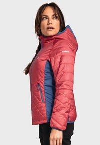 Rote und blaue isolierte Jacke mit einem gesteppten Design, ausgestattet mit Kapuze, Reißverschlusstaschen und einem Logo auf der Brust. Leichtes Material.