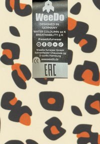 WeeDo-märke på tyg med en ljuskrämfärgad bakgrund och abstrakta svarta och orangeformer. Texten inkluderar skötselråd och varumärkesinformation.