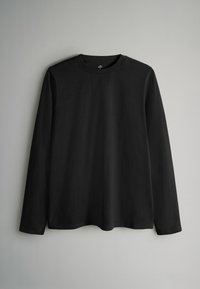 Tricou negru cu mâneci lungi, realizat din bumbac moale. Are un decolteu rotund și o croială lejeră cu margini netede. Fără modele vizibile sau elemente metalice.