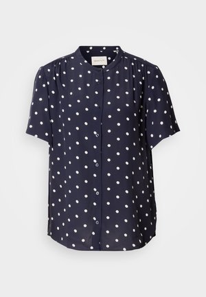 Tengerészkék, rövidujjú blúz fehér pöttyökkel, gumírozott elülső része gombos, kerek nyakkal rendelkezik. Könnyű anyagból készült.