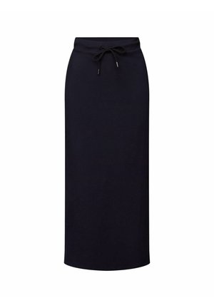 Kobieta ubrana w czarną spódnicę midi z sznurkiem, czarne sandały, paskowany top bikini i otwartą niebieską koszulę na guziki.