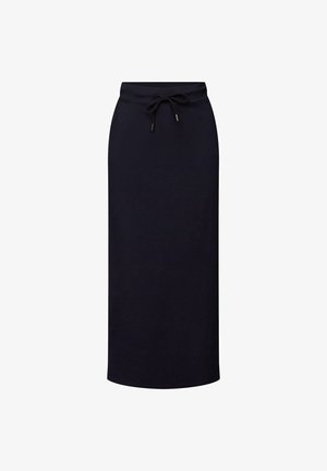 Kobieta ubrana w czarną spódnicę midi z sznurkiem, czarne sandały, paskowany top bikini i otwartą niebieską koszulę na guziki.