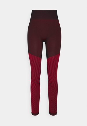 Leggings de talle alto en rojo oscuro y negro con acentos a rayas. Presentan una textura suave y un diseño ajustado para facilitar el movimiento.