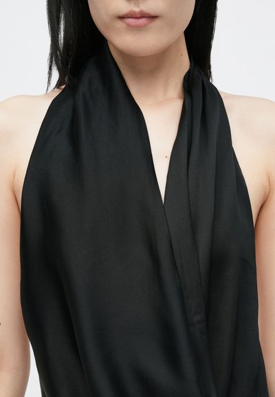Melnā halter topa blūze, izgatavota no gludas auduma, ar zemu kakla izgriezumu un plūstošu dizainu. Nav redzamu rakstu vai aksesuāru detaļu.