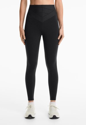 Leggings neri a vita alta con un motivo a rombi testurizzato in vita, finitura liscia, silhouette aderente e design alla caviglia.
