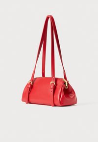 Κόκκινη, στρογγυλεμένη τσάντα χειρός από λείο δέρμα, με δύο μακριά λουριά, μεταλλικά στοιχεία σε χρυσό τόνο και κλείσιμο με φερμουάρ.
