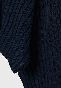 Tissu tricoté bleu marine foncé avec une texture côtelée verticale et un drapé plié, mettant en valeur le motif de point et la douceur.