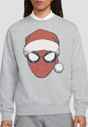Person wearing a light gray sweatshirt featuring a graphic of Spider-Man's mask with a red and white Santa hat.