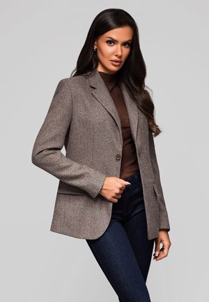Blazer ajusté marron en tissu texturé, doté d'une fermeture à un bouton, de revers crantés et de poches latérales. Porté sur un haut marron.