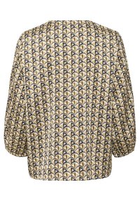 Blusa de manga corta con un patrón geométrico en tonos negro, blanco y dorado, con corte holgado y textura de tela suave.