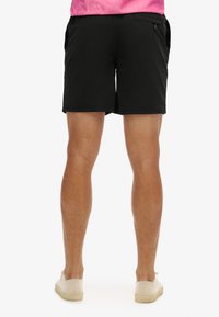Pantaloni corti neri con tasche laterali e posteriori, realizzati in un tessuto leggero, caratterizzati da una texture morbida e un fit rilassato.