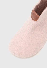 Lichtroze vilten pantoffel met een gladde textuur, voorzien van een gestikte naad en een bruine leren accent aan de bovenkant voor gemakkelijk aan- en uittrekken.