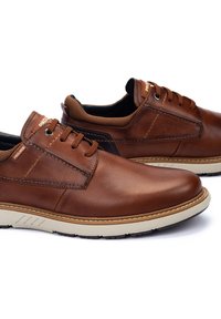 Scarpe in pelle marrone con finitura liscia, lacci e dettagli in tessuto. Presentano una suola in gomma beige e sottili dettagli di cucitura.