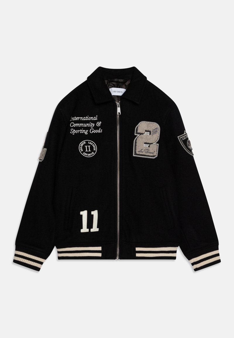 Veste varsity en laine noire avec fermeture éclair à l'avant, numéros en relief blancs (2, 11) et texte, poignets et ourlet à rayures côtelées, et patchs brodés.