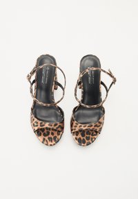 Lacets à talons ouverts en imprimé léopard avec des semelles intérieures en cuir noir et des brides de cheville ajustables. Dotés d'un talon épais et en matériau végan.