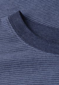 Gros plan sur un tissu côtelé bleu marine montrant des coutures détaillées autour d'un col rond d'un vêtement.