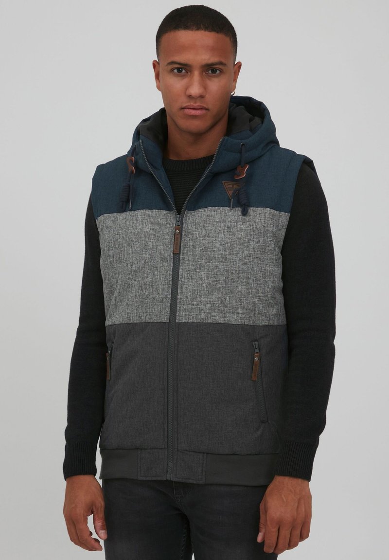 Die Weste mit Reißverschluss verfügt über ein farbblockiertes Design mit navyblauen, grauen und dunkelgrauen Paneelen. Texturierten Stoff mit verstellbarem Kapuzen und Taschen.