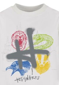 Hvid t-shirt med farverige dyretegn: rød løve, blå ravn, grøn slange, gul grævling, med et grå hashtag-graphic og "Hogwarts" tekst.