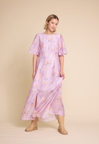 Maxikjole i lys lilla med blomsterdesign, korte flæseærmer, rund halsudskæring og et frontslids. Fremstillet af fløjlsagtigt stof.