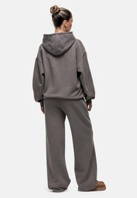Overmatige grijze hoodie met een trekkoord in de capuchon, gecombineerd met bijpassende baggy broek. Zachte stof met een eenvoudige, uniforme textuur.