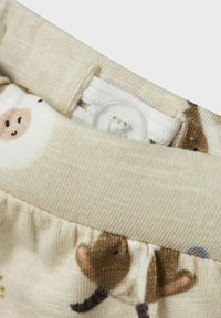 Katoenen shorts in een crèmekleur met dierenpatronen, een elastische tailleband en een knoopsluiting, benadrukken de zachte textuur van de stof.