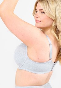 Harmaa puuvillainen bralette, jossa on säädettävät olkaimet, pyöristetty muoto ja hienovarainen brodeerattu yksityiskohta vyötäröllä lisäsuunnittelua varten.