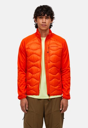 Leuchtend orangefarbene isolierte Jacke mit gestepptem Muster, mit Reißverschluss versehene Taschen und Stehkragen. Getragen über einem hellgelben Hemd, kombiniert mit braunen Hosen.