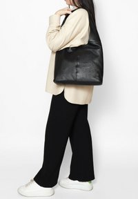 Zwarte leren tote bag met een zachte textuur, ruime body en minimalistisch ontwerp. Voorzien van brede straps voor comfortabel dragen.