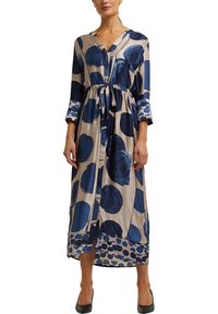 Long, collared dress with a tie waist, featuring large blue and navy circular patterns on a beige background. Lightweight, smooth fabric.