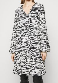 Abito a stampa zebra in bianco e nero con scollatura a V, collo arricciato, maniche lunghe e orlo a strati, realizzato in tessuto leggero.