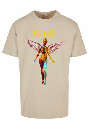 Béžové bavlnené tričko s grafikou stylizovanej anatomickej postavy s farebnými detailmi a anjelskými krídlami. Text: "NIRVANA" v žltej farbe.