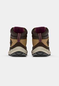 Botas de senderismo marrones y mostaza con cuellos acolchados, suelas de goma y un acento burdeos. Materiales de ante texturizado y nylon.
