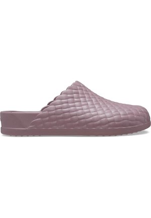 Sabots mauves à enfiler avec un motif texturé en matelassé et un bord festonné. Fabriqués en matériau flexible avec une semelle plate et sans quincaillerie visible.