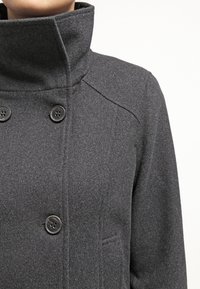 Grauer Wollmischmantel mit hohem Kragen, doppelt geknöpftem Verschluss und dezent strukturierter Oberfläche. Minimalistisches Design, keine Muster.