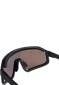 Čierne športové slnečné okuliare s tesným fitom, vybavené tmavými sklá a penovým obrancom obočia pre vyššie pohodlie. Súčasťou sú aj nastaviteľné nosné opierky.