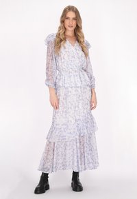 Flower printed maxi dress in transparent lavender fabric with ruffled sleeves, fitted waist, and layered skirt, combined with black chunky boots.