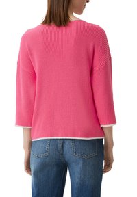 Rosa Strickpullover mit lockerem Schnitt, Dreiviertelärmeln und weißem Saum. Strukturierter Stoff von hinten gezeigt. Kombiniert mit blauen Jeans.