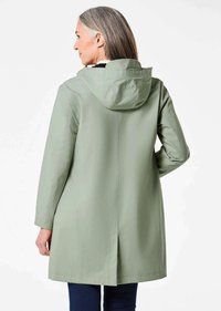 Lichtgroene waterdichte jas met een capuchon, lange mouwen en een rechte snit. Opvallende kenmerken zijn een rugventilatie en subtiele stiksels.