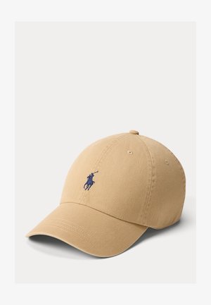 Beige katoenen baseballpet met een gebogen klep en een klein marineblauw geborduurd polospeler-logo aan de voorkant.