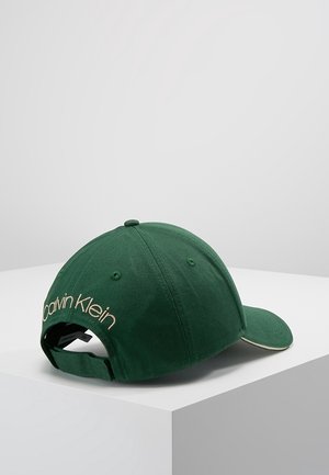 Dunkelgrüne Calvin Klein Baseballkappe mit verstellbarem Riemen, besticktem Logo auf der Rückseite und gebogenem Schirm, auf weißer Oberfläche präsentiert.