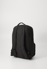Sac à dos noir avec dos rembourré, sangles ajustables et poche zippée ; fabriqué à partir de tissu durable ; présente des accents texturés et un design épuré.