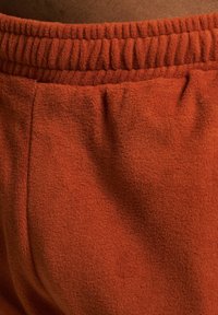 Orange fleece fabric with a textured finish, featuring a gathered elastic waistband and soft, plush appearance.