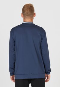 Mørkeblå langærmet skjorte med ribbet krave og hvide detaljer, lavet af glat og letvægtigt stof, designet til komfort.