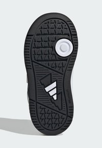 Crni gumeni potplat cipele s teksturiranim prijanjanjem, s bijelim okruglim detaljem i bijelim logotipom s tri pruge. Trojkutasti uzorak gaznoga sloja.