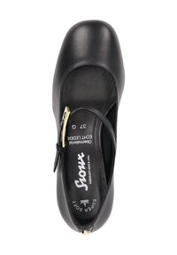 Chaussure plate en cuir noir avec un bout rond, une sangle réglable et des accents en métal doré. La semelle intérieure comporte des détails de marque et de taille.