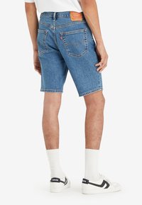 Blå denimshorts med rak benformation, med en märkesläderlapp på midjebandet och två bakfickor.