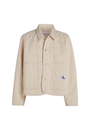 Bežová prešívaná bunda s gombíkovou prednou časťou, špicatým golierom a dvoma veľkými vreckami. Obsahuje nášivku loga na dolnom pravom rohu.