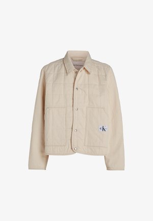 Bežová prešívaná bunda s gombíkovou prednou časťou, špicatým golierom a dvoma veľkými vreckami. Obsahuje nášivku loga na dolnom pravom rohu.