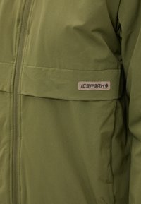 Olīvu zaļš jaka, kas izgatavota no viegla auduma, ar priekšējo rāvējslēdzēju, divām krūšu kabatām un izcilu Icepeak logo uzlīmi sānos.